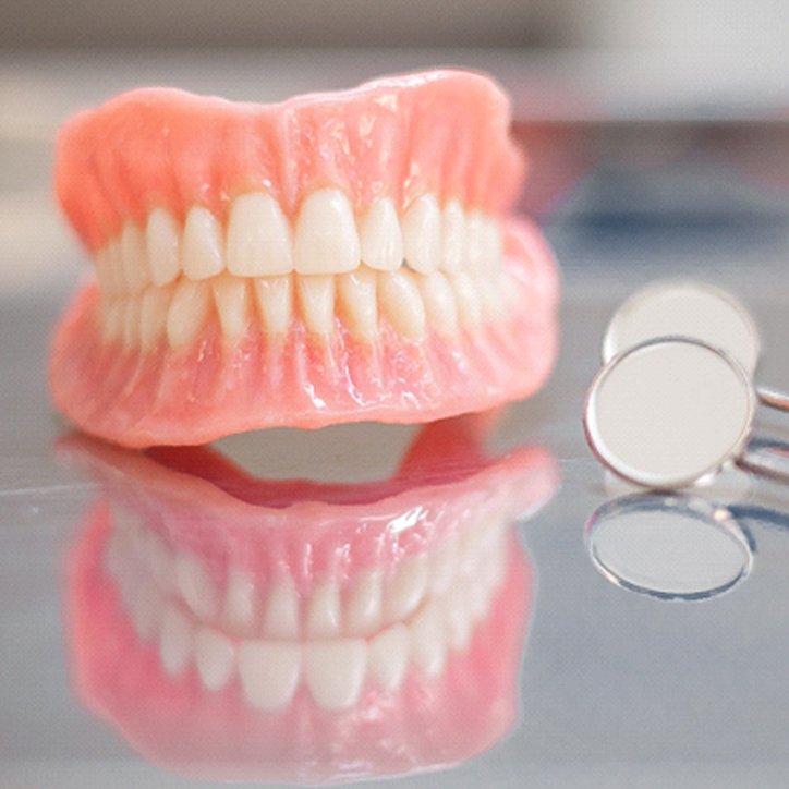 Pair of dentures sitting on a reflective table