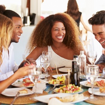 Group of friends laughing while eating meal at restaurant