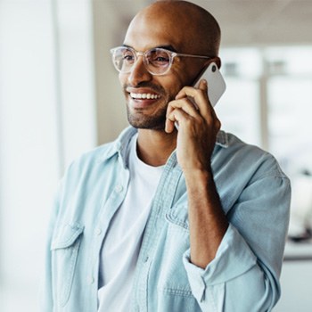 Man with glasses smiling while talking on phone