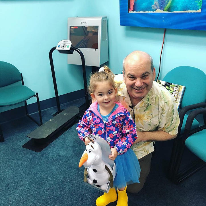 Pediatric dentist holding young patient in his lap