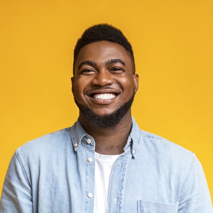 man smiling brightly against a yellow background