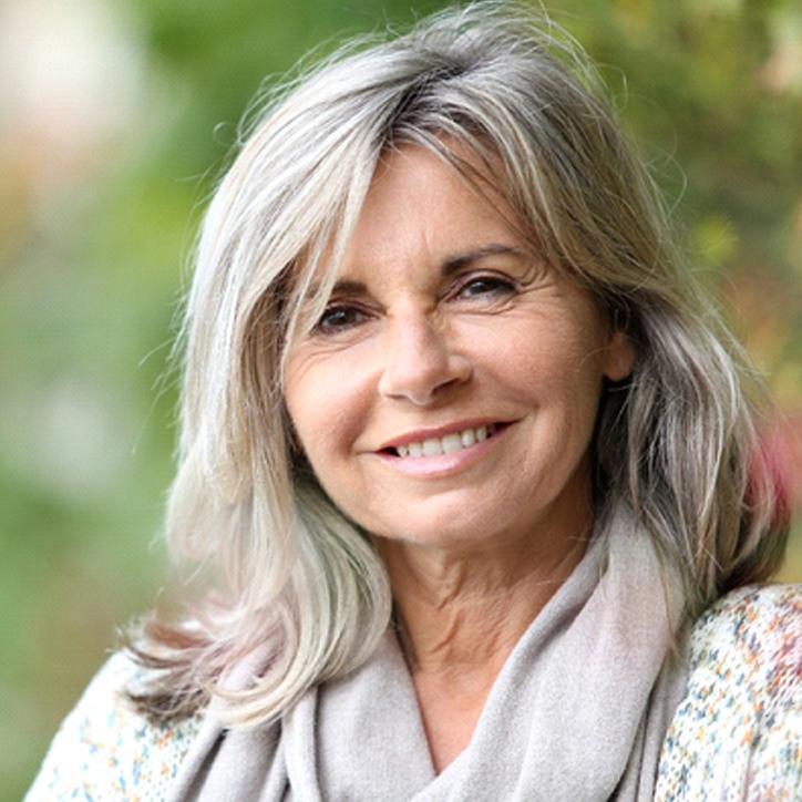 Older woman with grey hair and scarf outside smiling