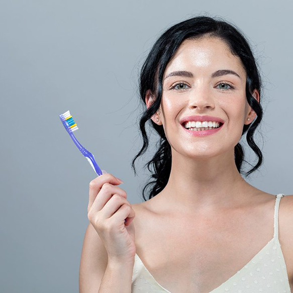 Woman holding purple toothbrush while smiling