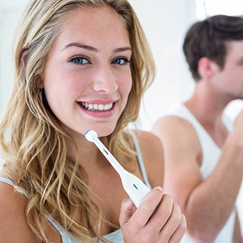 Woman holding toothbrush next to man and smiling