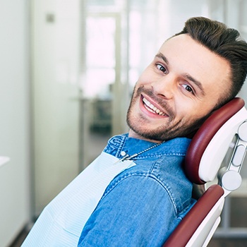Man in denim shirt smiling while in the dental chair