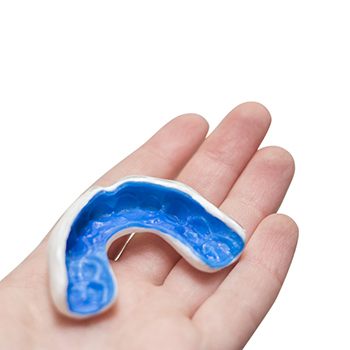 Close up of someone holding a blue mouthguard