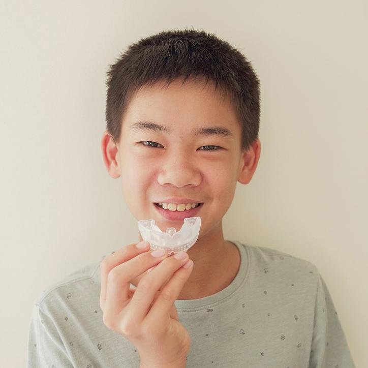 young boy holding custom-made athletic mouthguard 