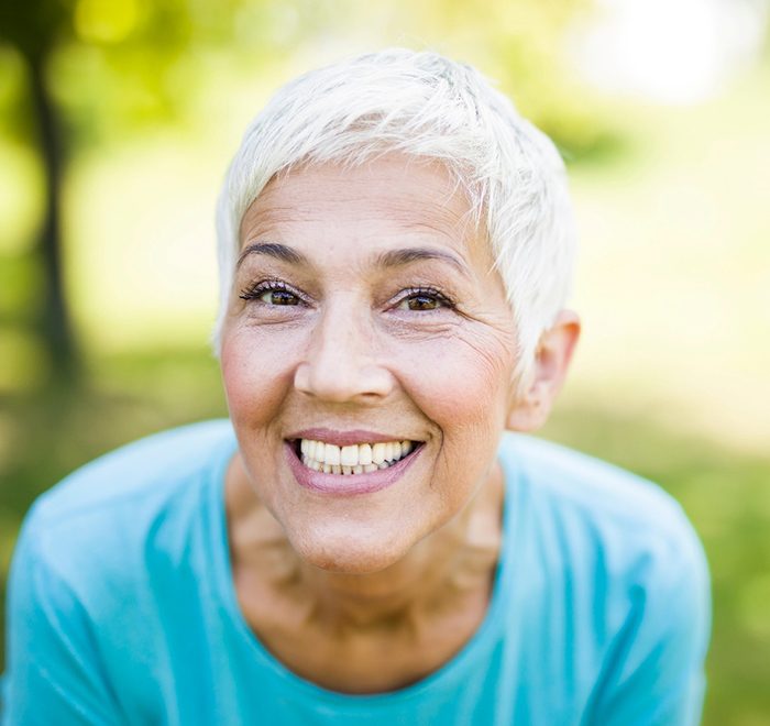 Senior woman in blue shirt showing her smile