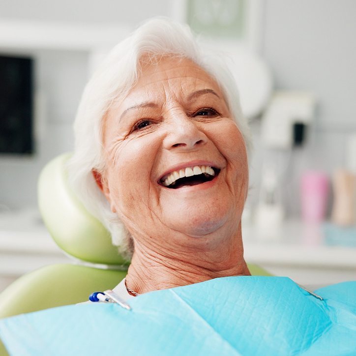 Senior woman sitting back in dental chair and laughing