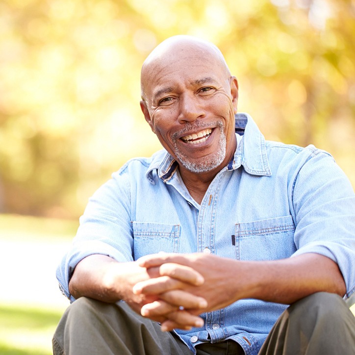 Older man sitting outside with his hands folded