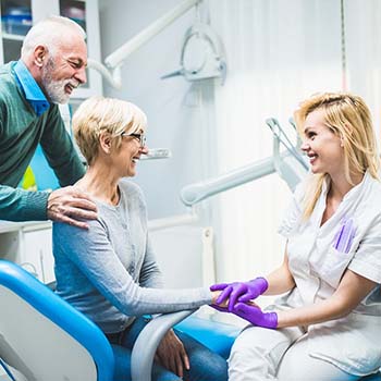 Older couple speaking with an implant dentist in Long Beach