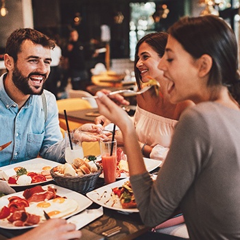 Group of friends smiling while eating lunch at restaurant