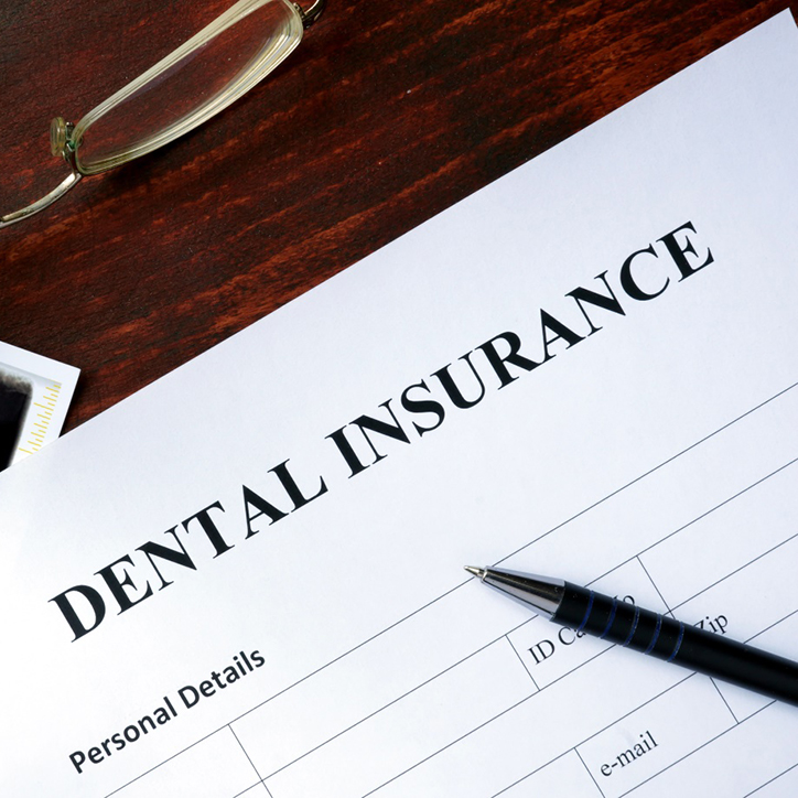 Close-up of dental insurance form with pen and glasses