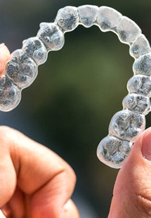 Close up of hand holding a clear aligner