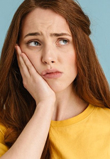 Woman rubbing her jaw after taking a sip of her drink