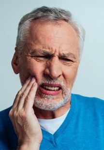 a man touching his cheek due to tooth pain