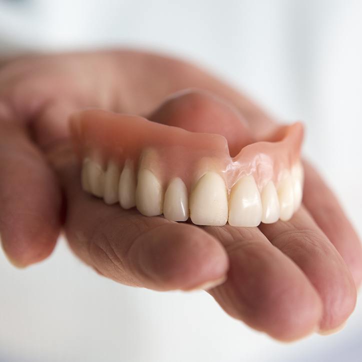 Hand holding a full denture