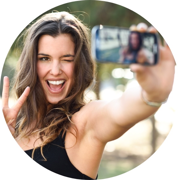 Smiling woman taking picture after cosmetic dentistry