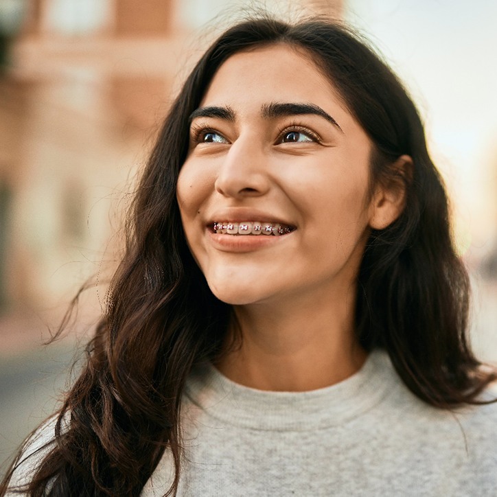 Teenage girl in grey shirt outside smiling with braces in Long Beach, NY