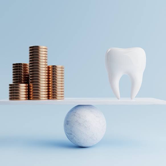 A fake tooth and golden coins on a balancing scale