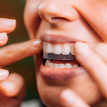 A woman using teeth whitening strips 