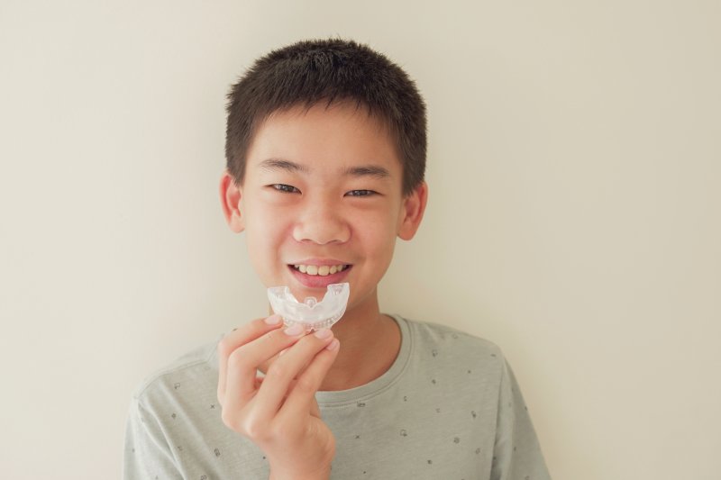 Boy holding mouthguard up to his smile