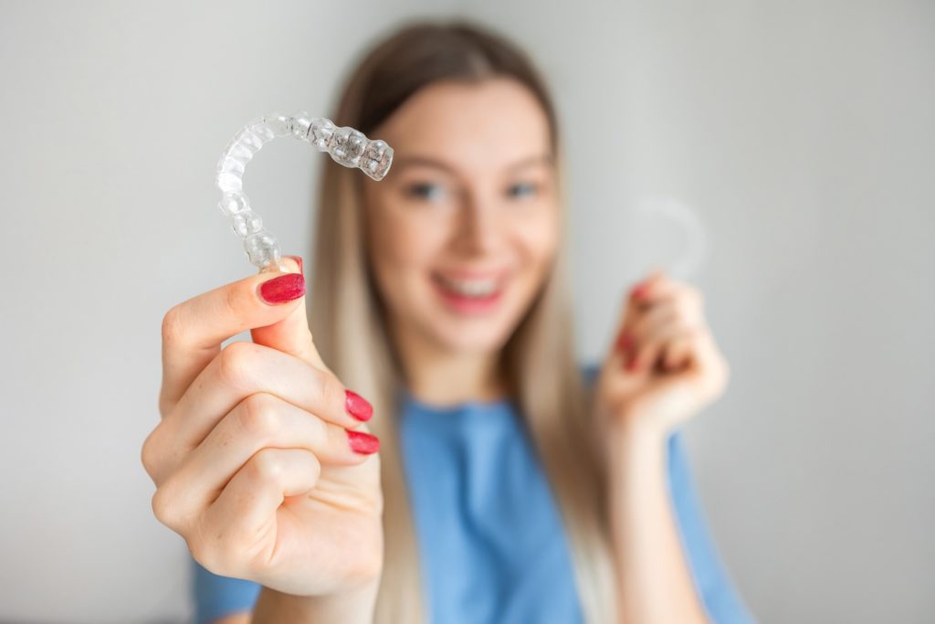 Patient smiling while holding clear aligner